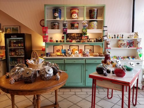 A cozy candy shop featuring colorful jars of sweets, a vintage display, and a variety of treats on shelves.