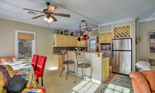 Cozy kitchen and dining area with colorful decor, bar stools, and a dining table set for a meal. Bright and inviting space.