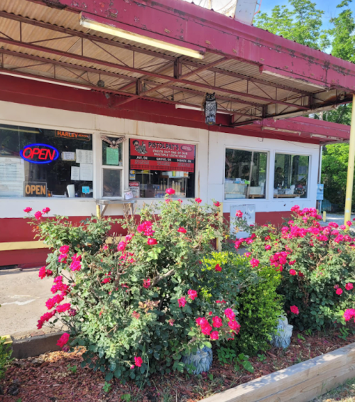 A red and white diner with an "Open" sign, surrounded by blooming pink roses.