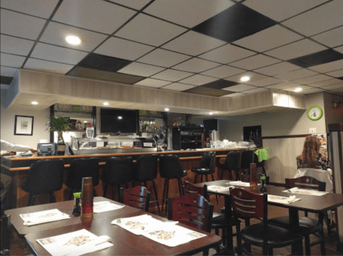 Interior of a restaurant featuring a bar area, tables with menus, and a cozy atmosphere.