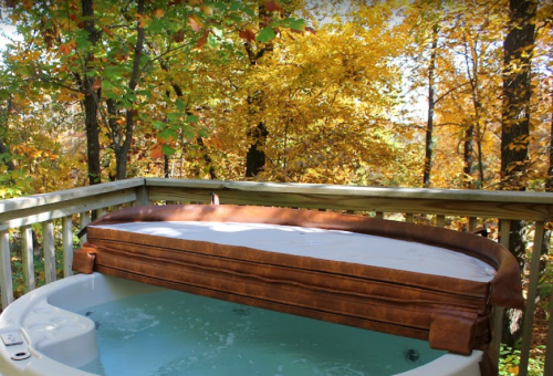 A hot tub on a wooden deck surrounded by vibrant autumn foliage.