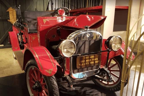 A vintage red fire truck from 1917, featuring a shiny chrome front and wooden ladder on the back.