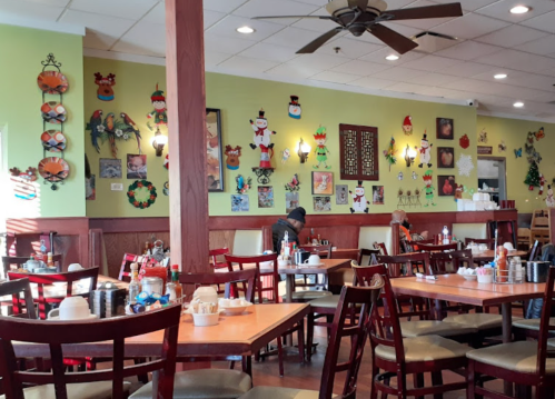 Cozy restaurant interior with colorful wall decorations, tables set for dining, and a few patrons enjoying their meals.