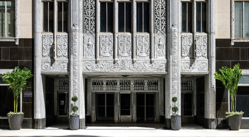 Art Deco entrance of the International Building, featuring intricate carvings and large glass doors.