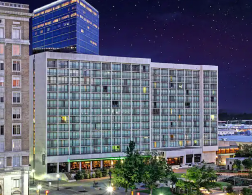 A modern hotel building at night, featuring large glass windows and a starry sky in the background.