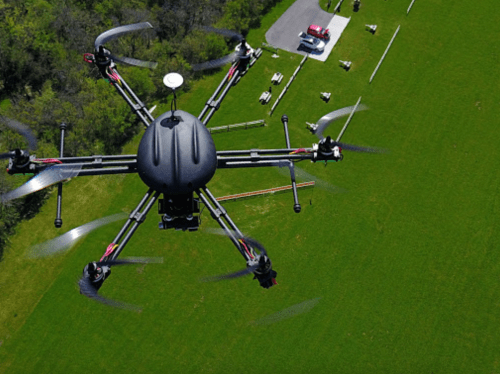 Aerial view of a drone flying over a green field with a fire truck parked nearby.