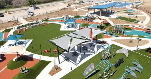 Aerial view of a colorful playground with various play structures, shaded areas, and open green spaces.