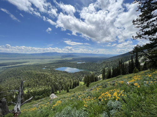 A scenic view of a valley with two lakes, surrounded by lush greenery and mountains under a partly cloudy sky.