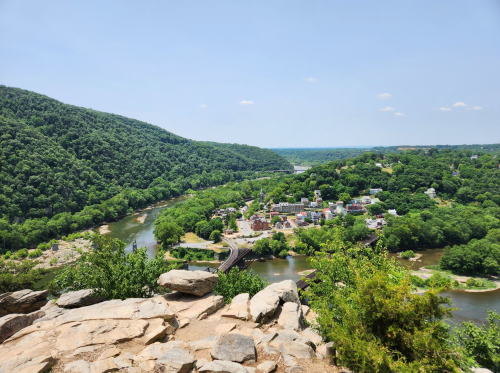 A scenic view of a river winding through green hills, overlooking a small town nestled among the trees.