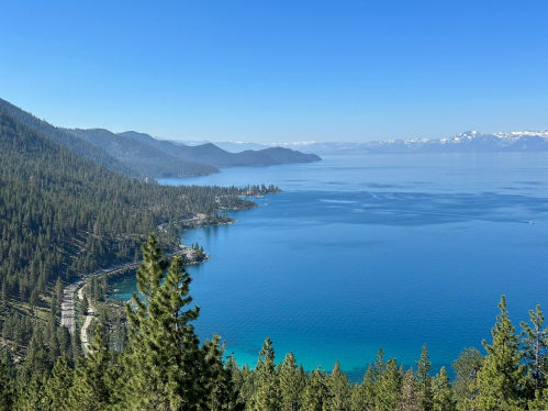 A scenic view of Lake Tahoe, surrounded by mountains and lush forests under a clear blue sky.