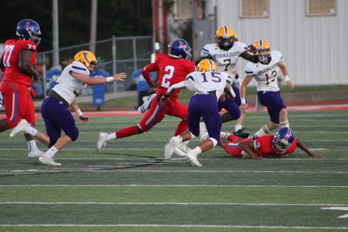 A football game scene with players in action, one running with the ball while others pursue and tackle.