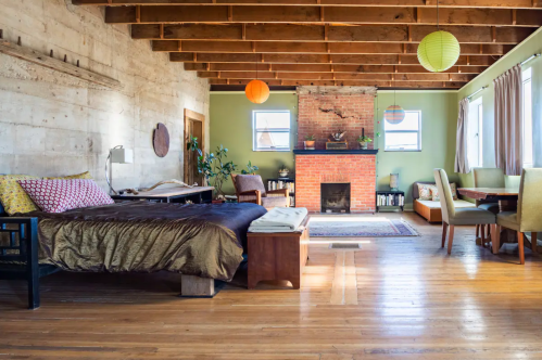 Cozy living space featuring a bed, fireplace, dining area, and large windows with colorful lanterns hanging from the ceiling.