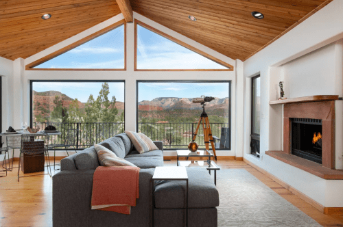 Cozy living room with a modern design, large windows showcasing mountain views, and a telescope by the fireplace.