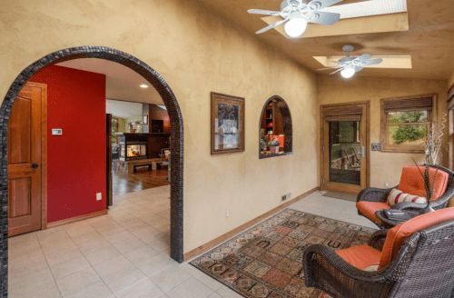 A cozy entryway with arched doorways, a patterned rug, and seating, featuring warm colors and natural light.