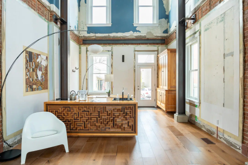 A modern interior with exposed brick walls, wooden flooring, and a stylish kitchen island in a bright, airy space.