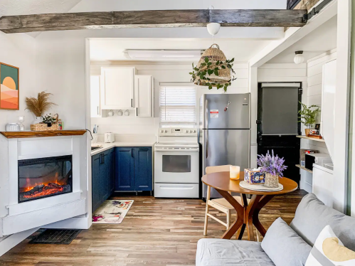 Cozy kitchen and living area with blue cabinets, a fireplace, and a round dining table, featuring warm wood accents.