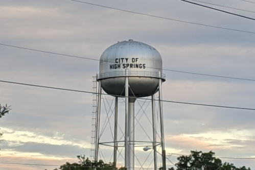 Water tower with "City of High Springs" written on it, set against a cloudy sky.