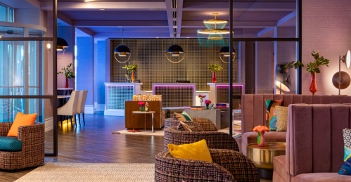 Modern hotel lobby featuring colorful seating, stylish decor, and a vibrant reception area with floral arrangements.
