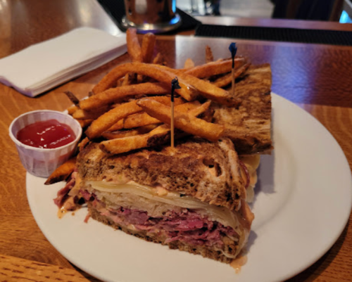 A hearty sandwich with layers of meat and cheese, served with crispy fries and a side of ketchup.