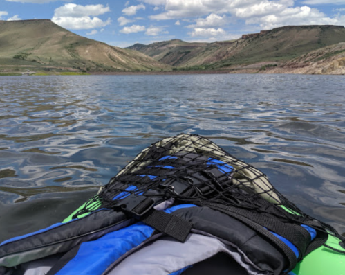A kayak on calm water with mountains and blue sky in the background, showcasing a peaceful outdoor scene.