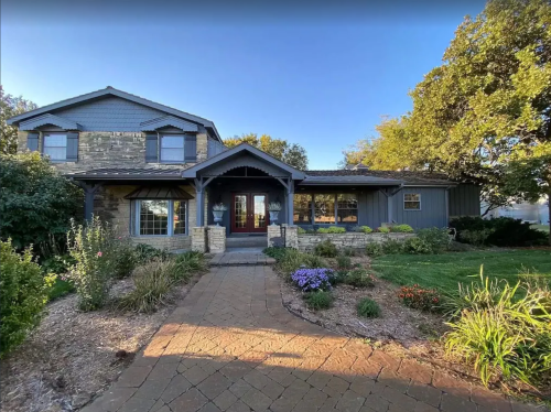 A charming two-story house with stone accents, a landscaped front yard, and a welcoming pathway.