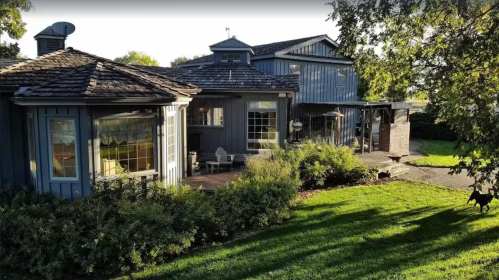 A charming blue house with a shingled roof, surrounded by lush greenery and a well-maintained garden.