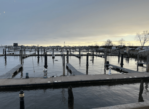 A calm marina at dusk with empty boat docks and still water reflecting the sky.