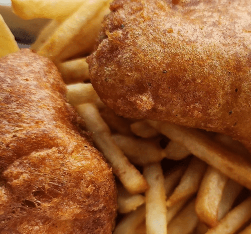 Close-up of crispy fried fish fillets resting on a bed of golden French fries.