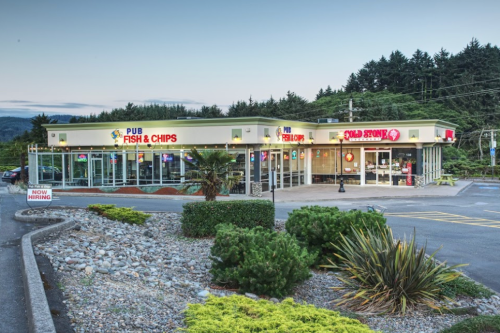 A seafood restaurant with a bright sign, surrounded by greenery and a parking lot, set against a forested backdrop.