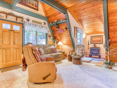 Cozy living room with wooden beams, a comfortable chair, and a small fireplace, decorated with rustic accents.