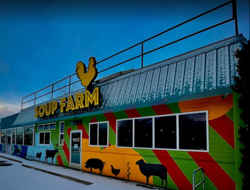 Colorful exterior of Soup Farm restaurant with animal silhouettes and a rooster sign, set against a snowy backdrop.