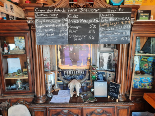 A rustic bar display with a chalkboard menu listing beers, ciders, and drafts, set in a cozy, vintage environment.