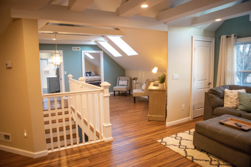 Bright, modern living space with wooden floors, skylights, and a cozy seating area. Stairs lead to an upper level.