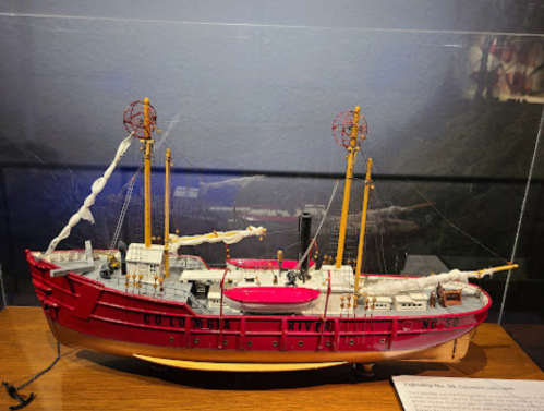 A detailed model of a vintage ship named "Columbia River," featuring red hull and tall masts, displayed on a wooden base.