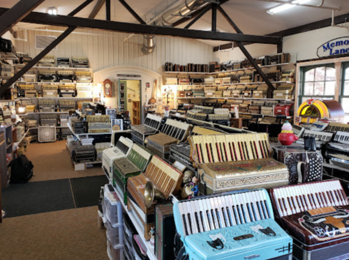 A spacious room filled with various accordions displayed on shelves and tables, creating a vibrant musical atmosphere.