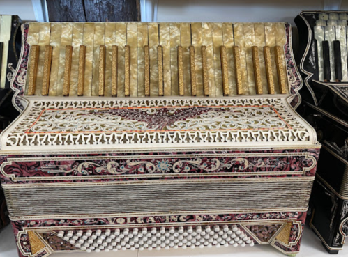 A beautifully decorated accordion with intricate designs and golden keys, displayed in a shop.
