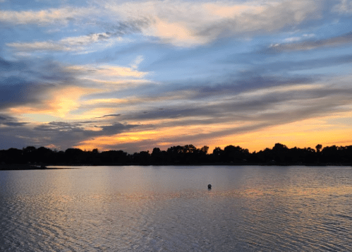 A serene lake at sunset, with colorful clouds reflecting on the water's surface.
