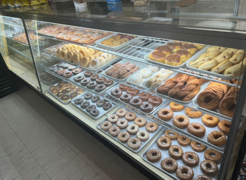 A display case filled with various types of donuts and pastries, showcasing a colorful assortment.