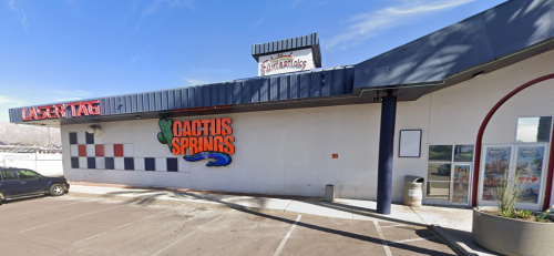 Exterior of a building featuring "Cactus Springs" signage and a laser tag area, with a clear blue sky above.