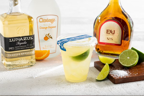 A refreshing cocktail with lime, surrounded by bottles of tequila, orange liqueur, and brandy, plus lime wedges and salt.