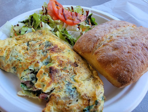 A plate with a vegetable omelette, a side salad with tomato, and a piece of bread.
