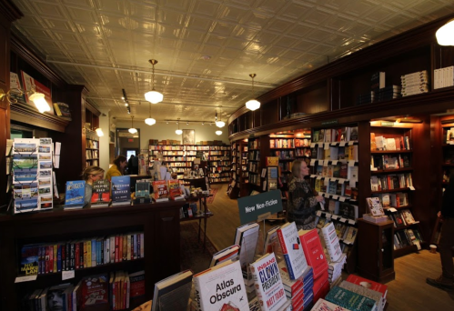 A cozy bookstore interior with wooden shelves filled with books and warm lighting, inviting readers to explore.