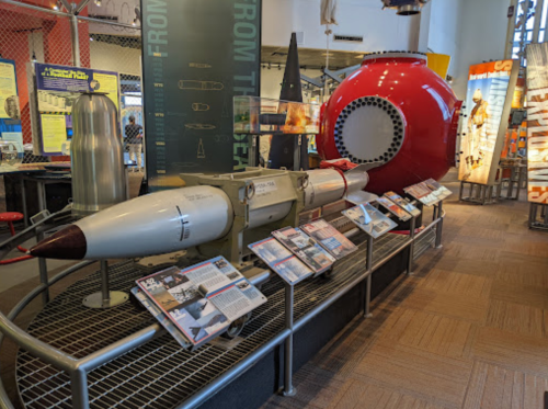 A display featuring a missile and a red underwater capsule, surrounded by informational panels in a museum setting.
