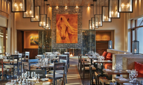 Elegant restaurant interior with wooden decor, a large horse painting, and tables set for dining under warm lighting.