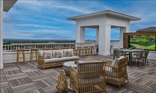 Rooftop terrace with seating, a table, and a large screen, overlooking a scenic view under a blue sky.