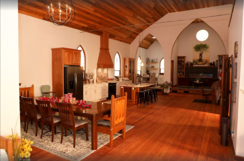 Spacious kitchen and dining area with wooden accents, large table, and open layout featuring arched windows.
