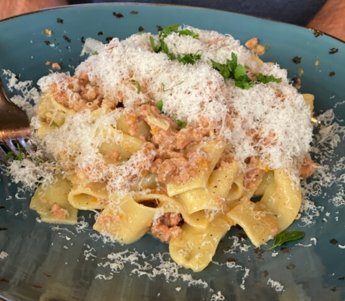 A plate of pasta topped with a creamy sauce and grated cheese, garnished with fresh herbs.