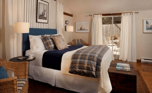 Cozy bedroom with a blue headboard, plaid bedding, and natural light from sliding doors leading to a patio.