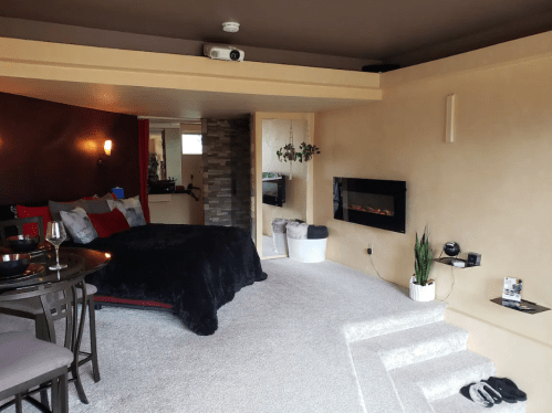 Cozy interior featuring a bed, dining area, and modern fireplace, with soft lighting and plush decor.