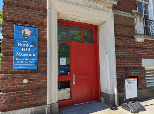 Entrance to the Bunker Hill Museum, featuring a red door and a sign about the Boston National Historical Park.
